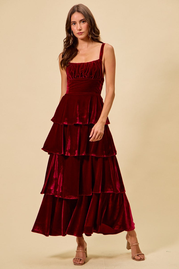 Woman wearing a burgundy velvet dress against a beige background