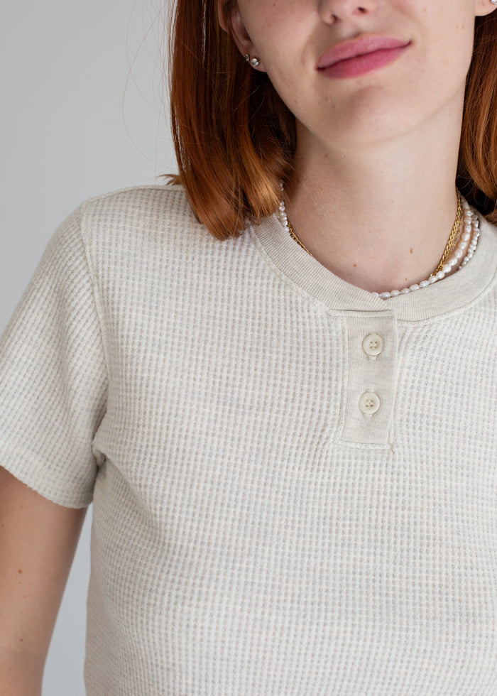 Person wearing a textured beige shirt with a plain background